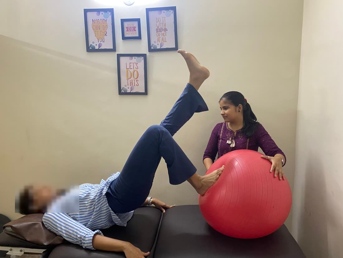Female physiotherapist guiding a patient through exercise-ball leg work at Physiotrix Ballygunge